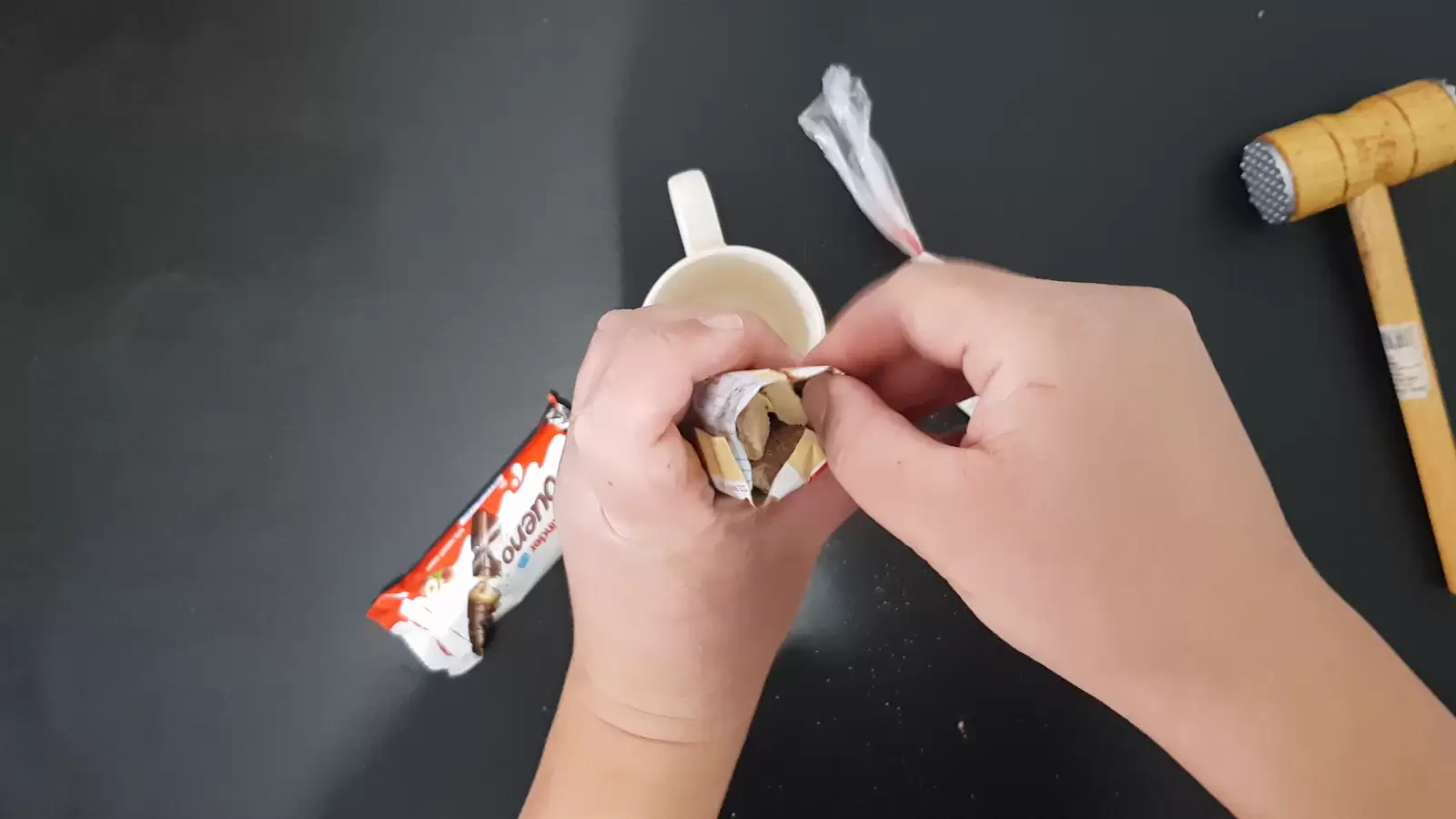 Whipped cream, a cup, Kinder Bueno, two wooden sticks, a kitchen hammer