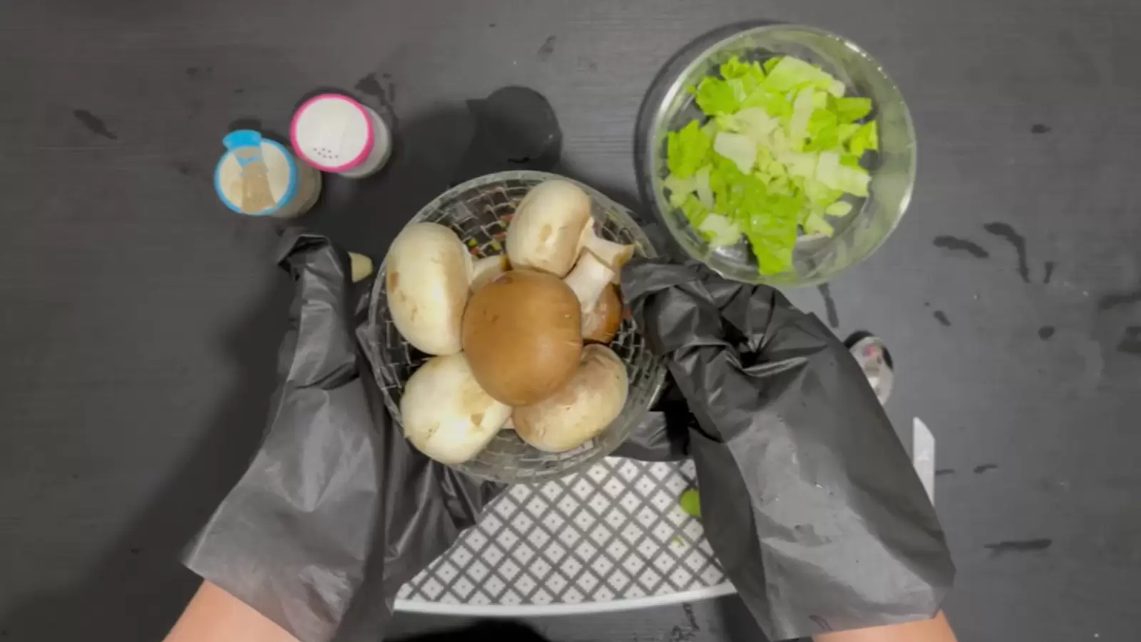 Bowl with lettuce, bowl with mushrooms, jar of salt, jar of pepper, cutting board