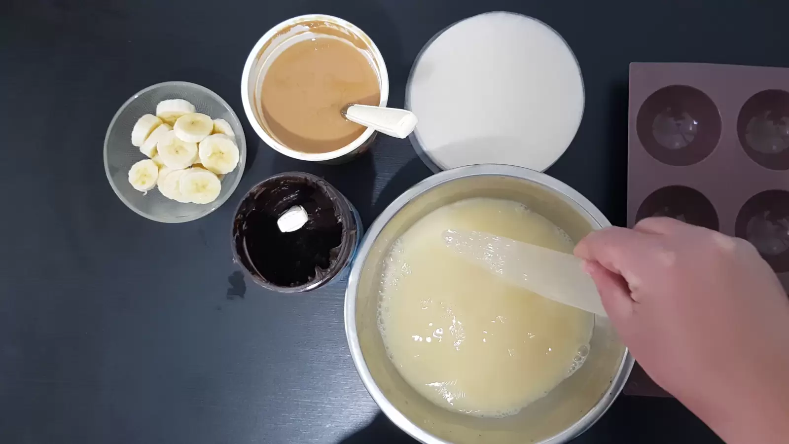 Muffin pan, rice paper, peanut butter jar, chocolate jar, bowl of sliced ​​bananas, rice paper in large bowl with mixture