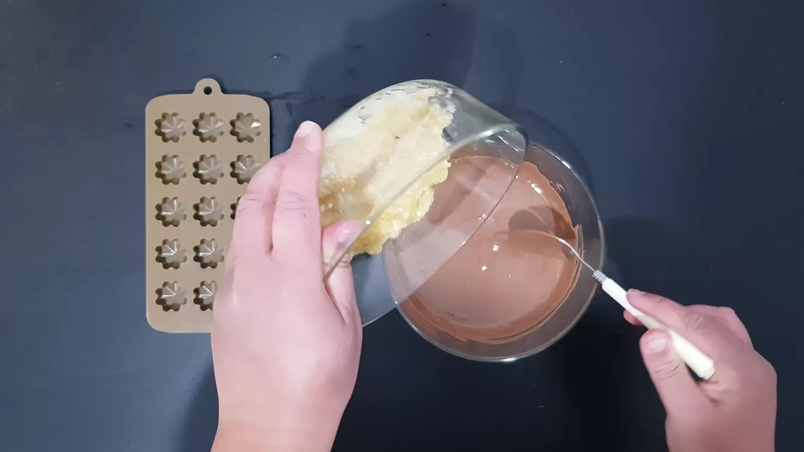 A bowl of bananas and a fork are poured into a bowl of milk chocolate, a mold