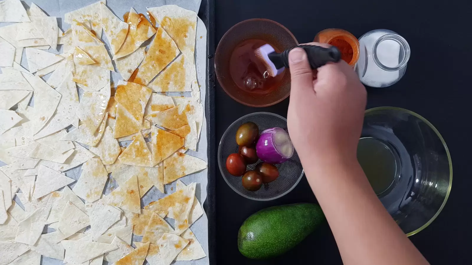 Spices, bowl with oil, empty bowl, tomatoes, purple onion, avocado, pan with cut tortillas