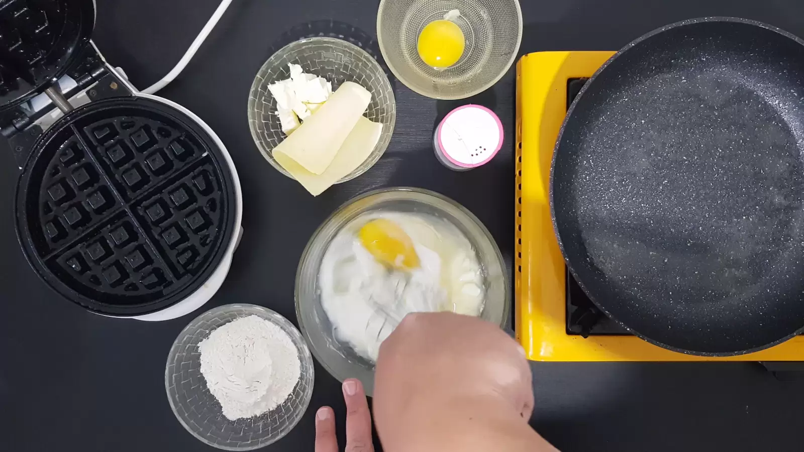 Whisk in a bowl. Bowl with flour, bowl with egg, bowl with cheeses. pan. Waffle maker.