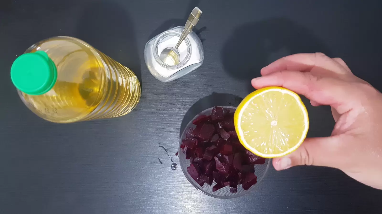 Half a lemon, a jar of salt with a spoon, a bottle of olive oil, a bowl of beets
