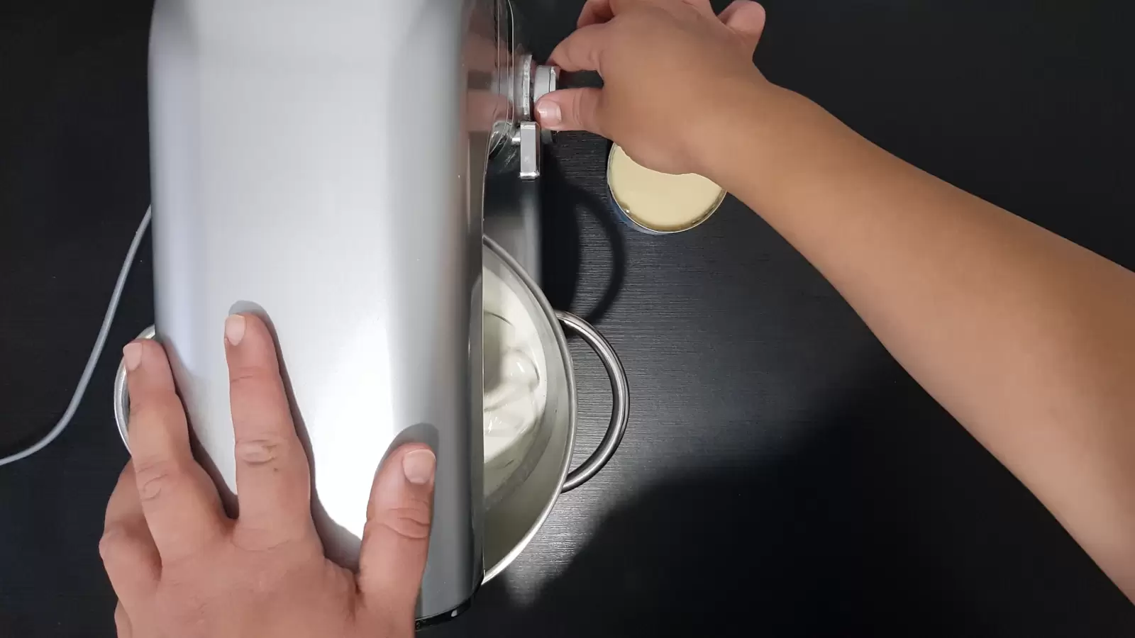 a bowl with whipping cream in a mixer, a can of condensed milk