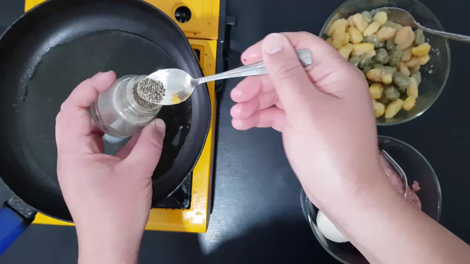 a jar with black pepper and a spoon, a pan, a bowl with gnocchi