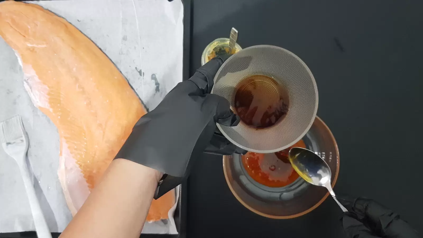 Bowl with soy, jar of crushed garlic, bowl with sauce, baking dish with salmon and brush