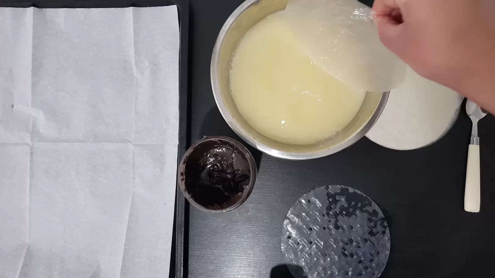 Rice paper in a bowl with water and egg, a jar with chocolate spread and a spoon, rice paper on the table, a baking sheet with baking paper