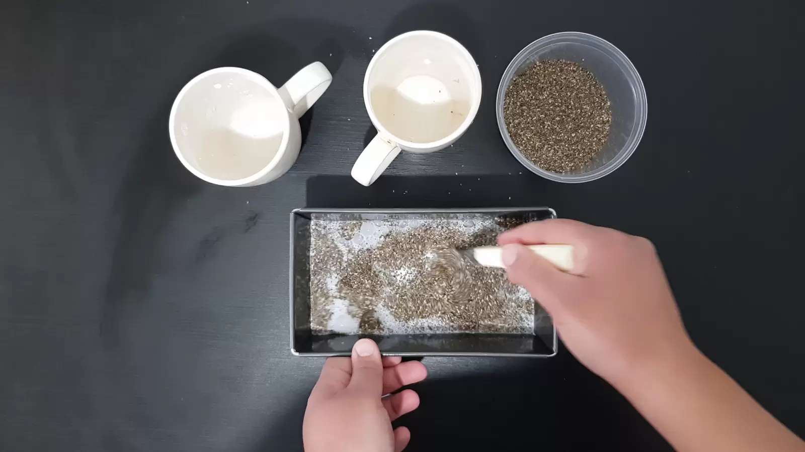 Two glasses, a box of chia, a mold with chia and milk, a spoon