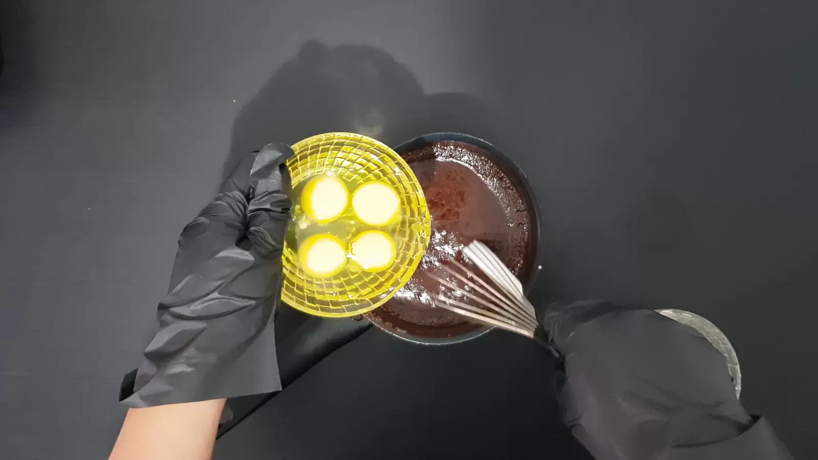 Bowl with chocolate batter, bowl with 4 eggs, whisk