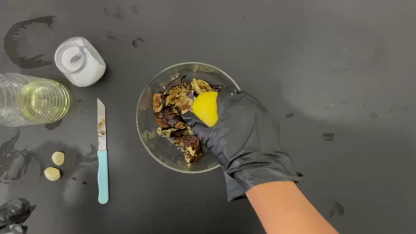 Bowl with diced eggplant, half a lemon, jar of salt, bottle of oil, knife, 2 garlic
