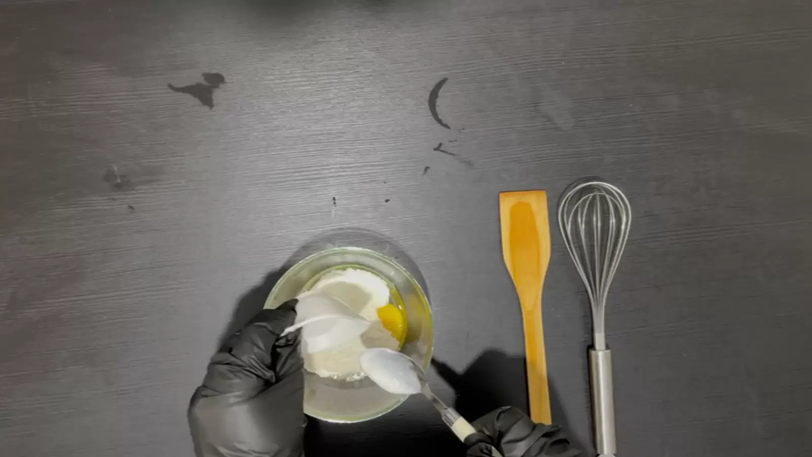 Whisker, wooden spoon, bowl with batter and spoon