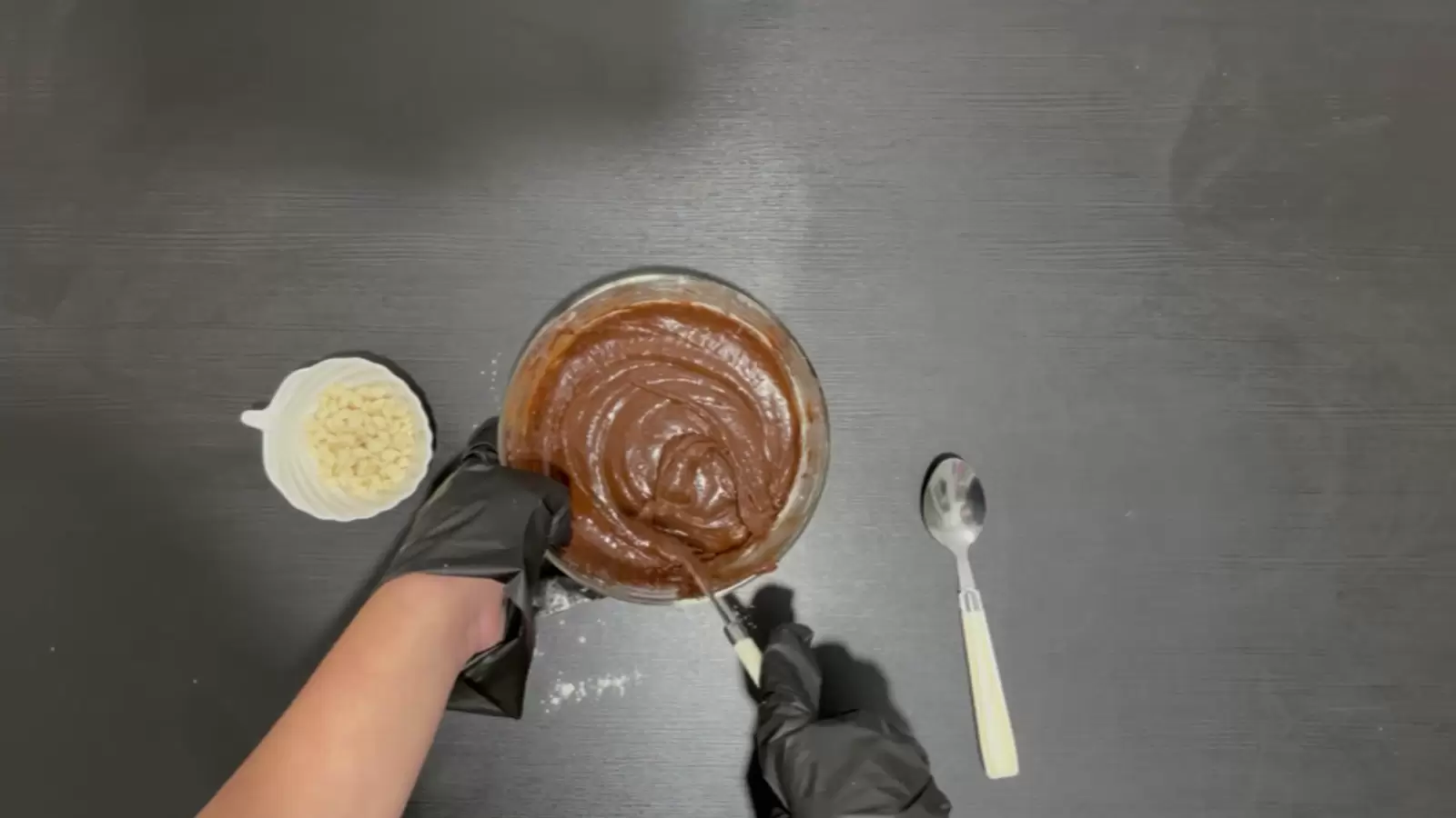 Bowl with chocolate batter, bowl with white chocolate chips, spoon.