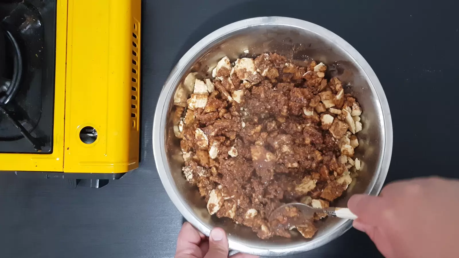 A bowl with biscuits and chocolate mixture on top, a mixing spoon