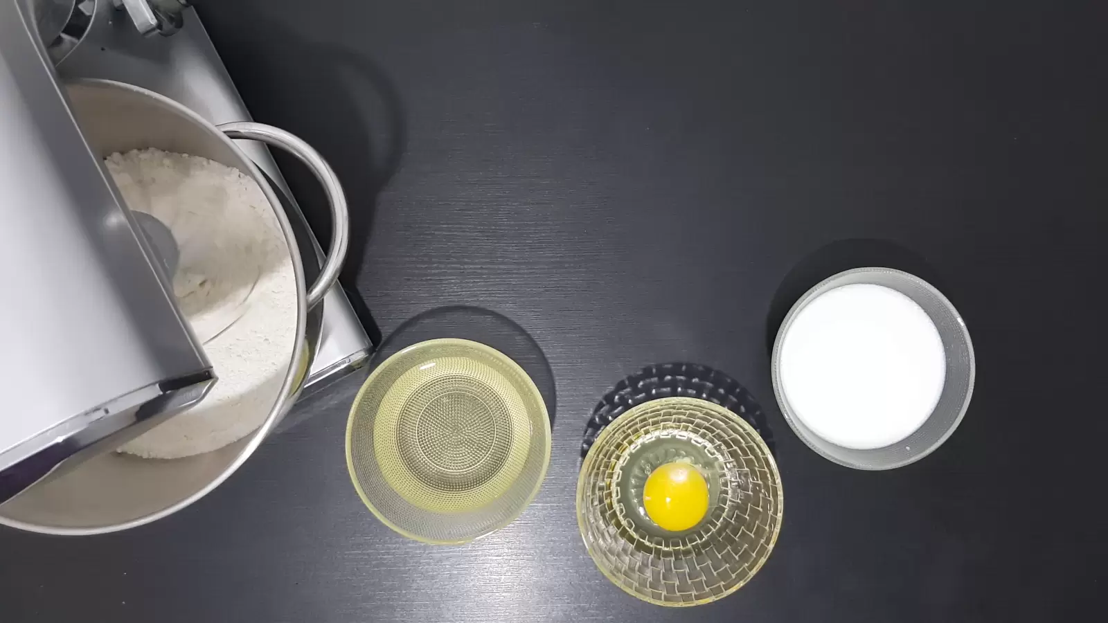 Mixer with mixture, bowl with oil, bowl with egg, bowl with milk