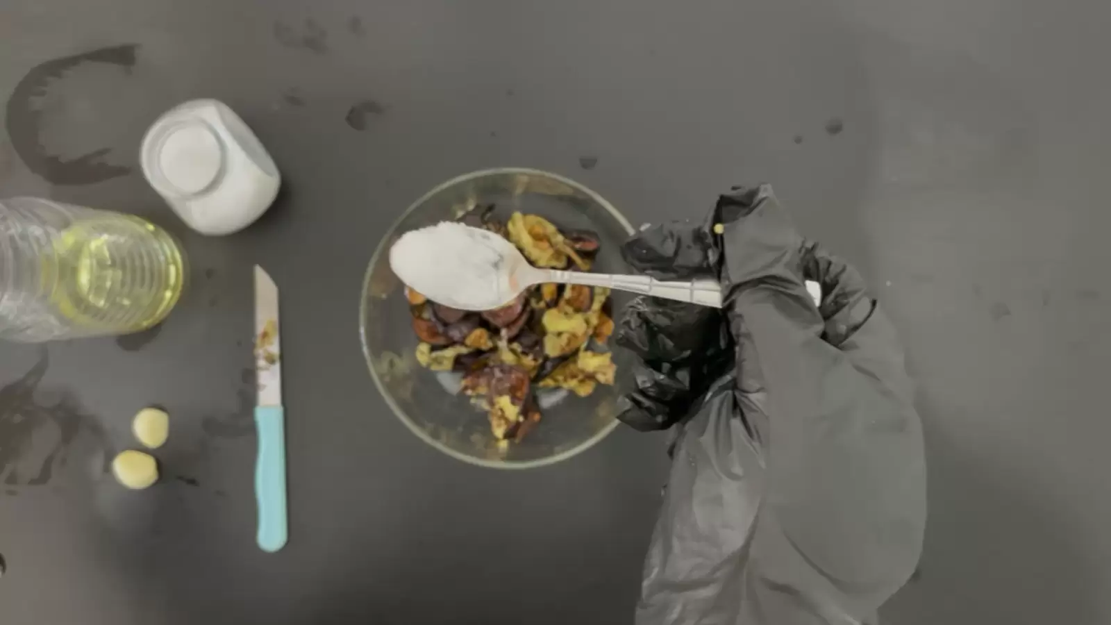 Bowl with diced eggplant, half a lemon, jar and spoon of salt, bottle of oil, knife, 2 garlic