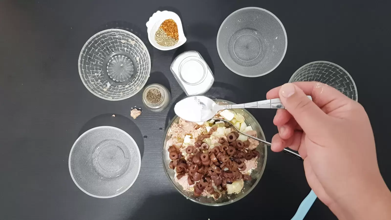 A bowl with olives, a bowl with spices, a teaspoon of salt, three empty bowls