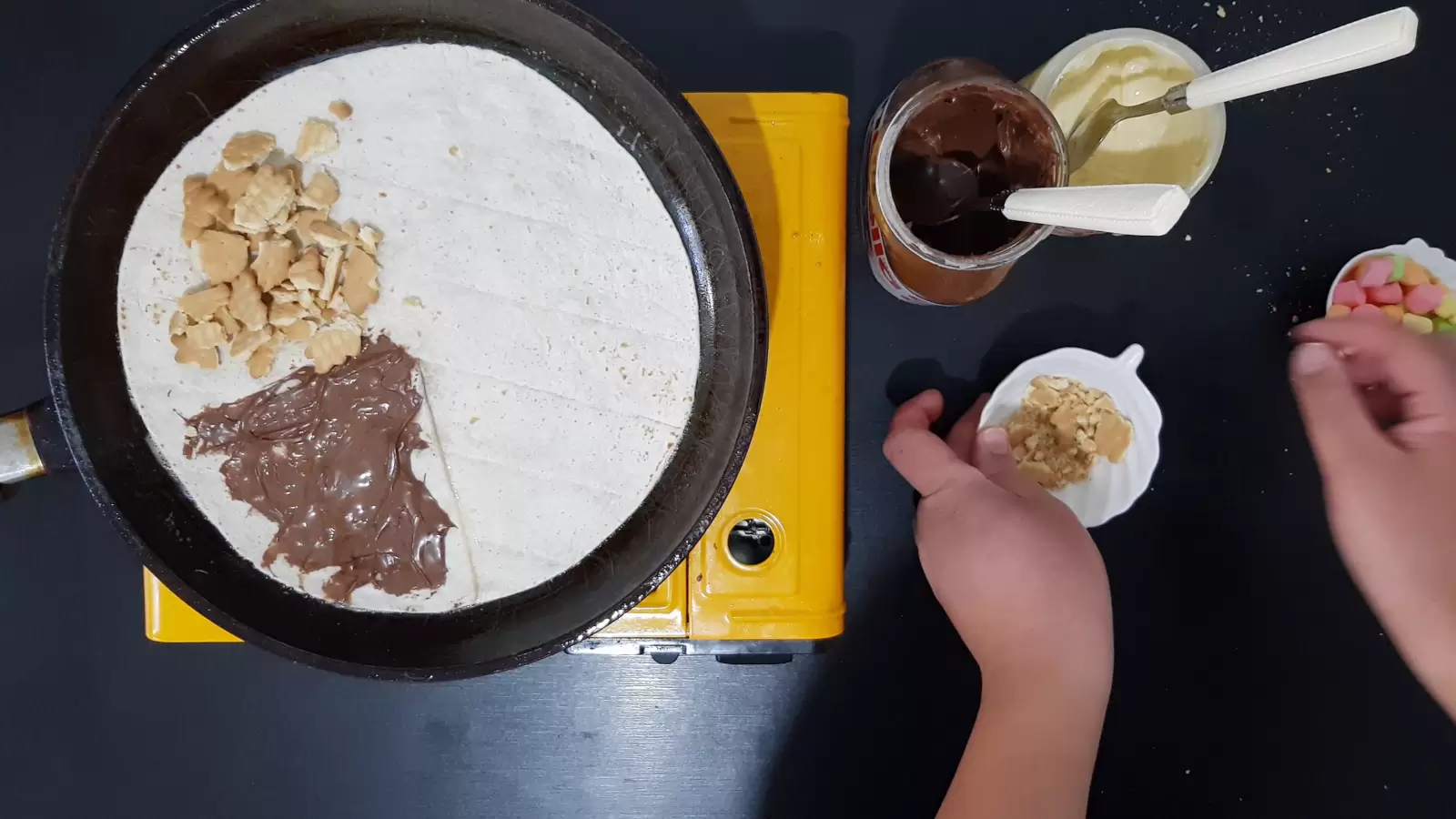 Biscuits bowl, white chocolate jar, Nutella chocolate jar, marshmallow bowl, tortilla in a pan with chocolate and biscuits