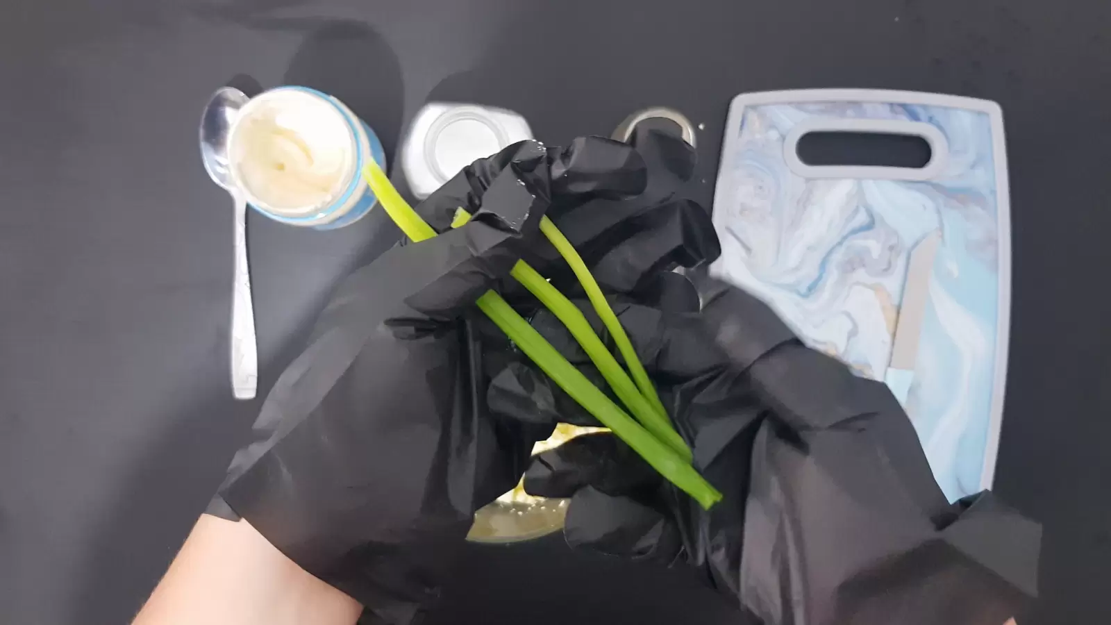 Cutting board, mayonnaise jar and spoon, green onion stalks
