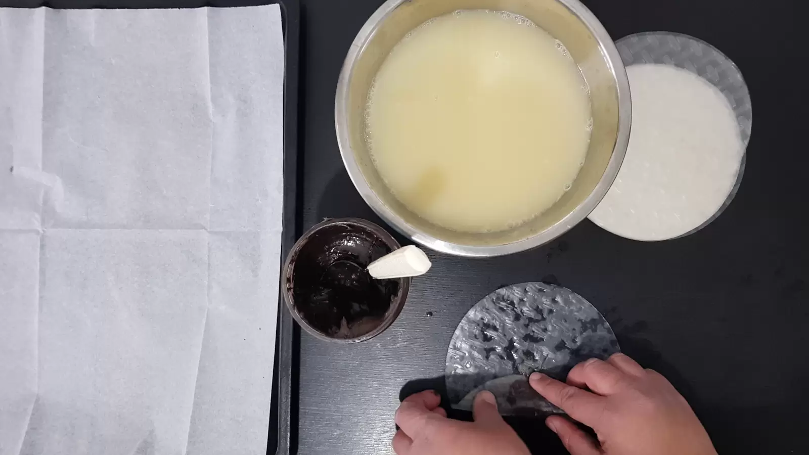 Rice paper, bowl with water and egg, jar with chocolate spread and spoon, rolled rice paper, baking sheet with baking paper