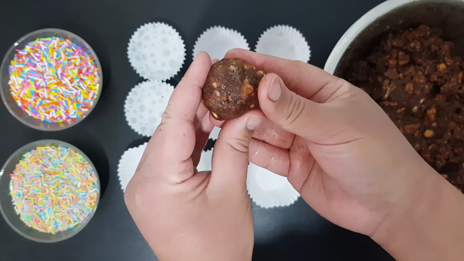 Chocolate ball, bowl with mixture, baking cups, rainbow sprinkles