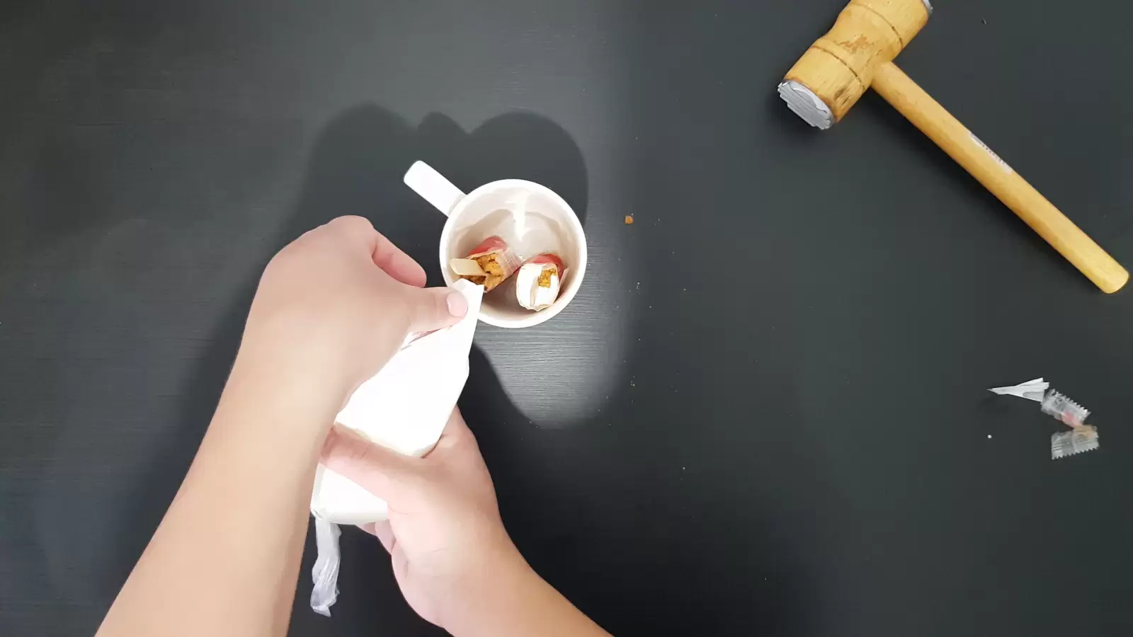 A kitchen hammer, a glass with two biscuits, whipped cream