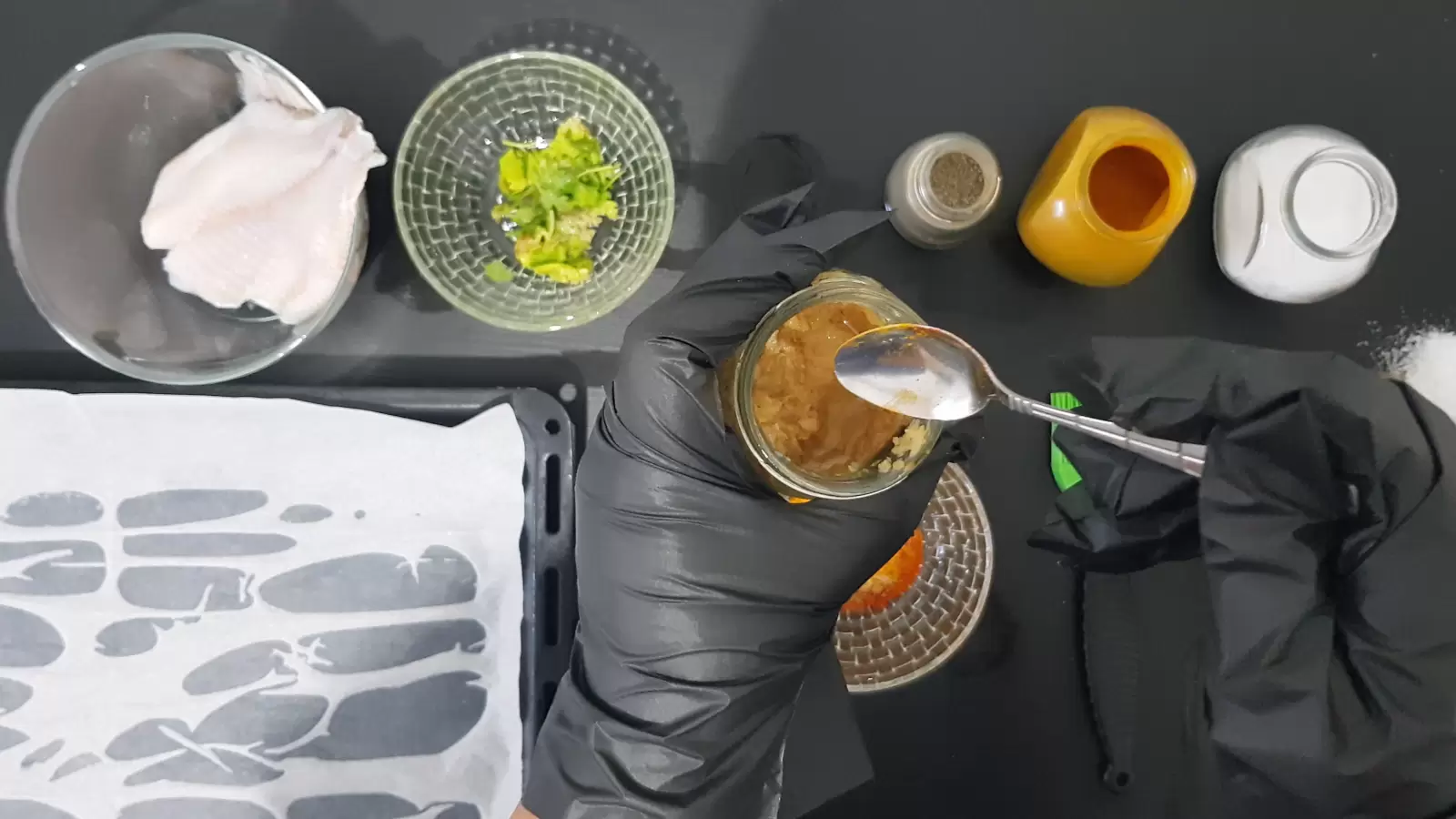 Turmeric, salt, coriander, oven tray, tilapia fish, and a teaspoon with garlic