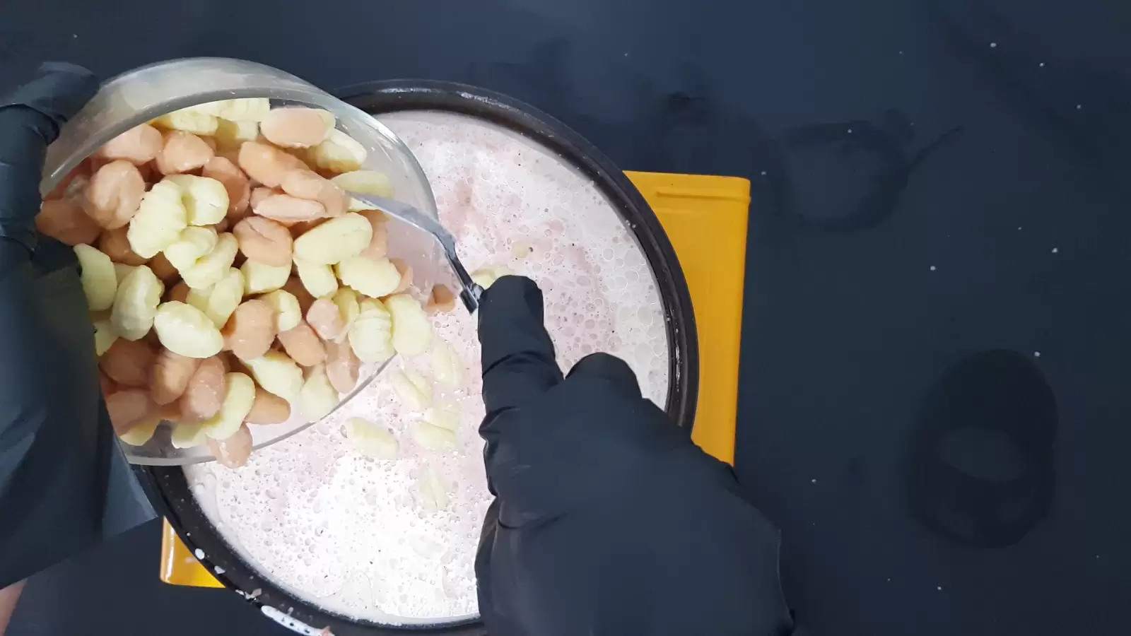 A pan with sauce and a bowl of gnocchi poured into it