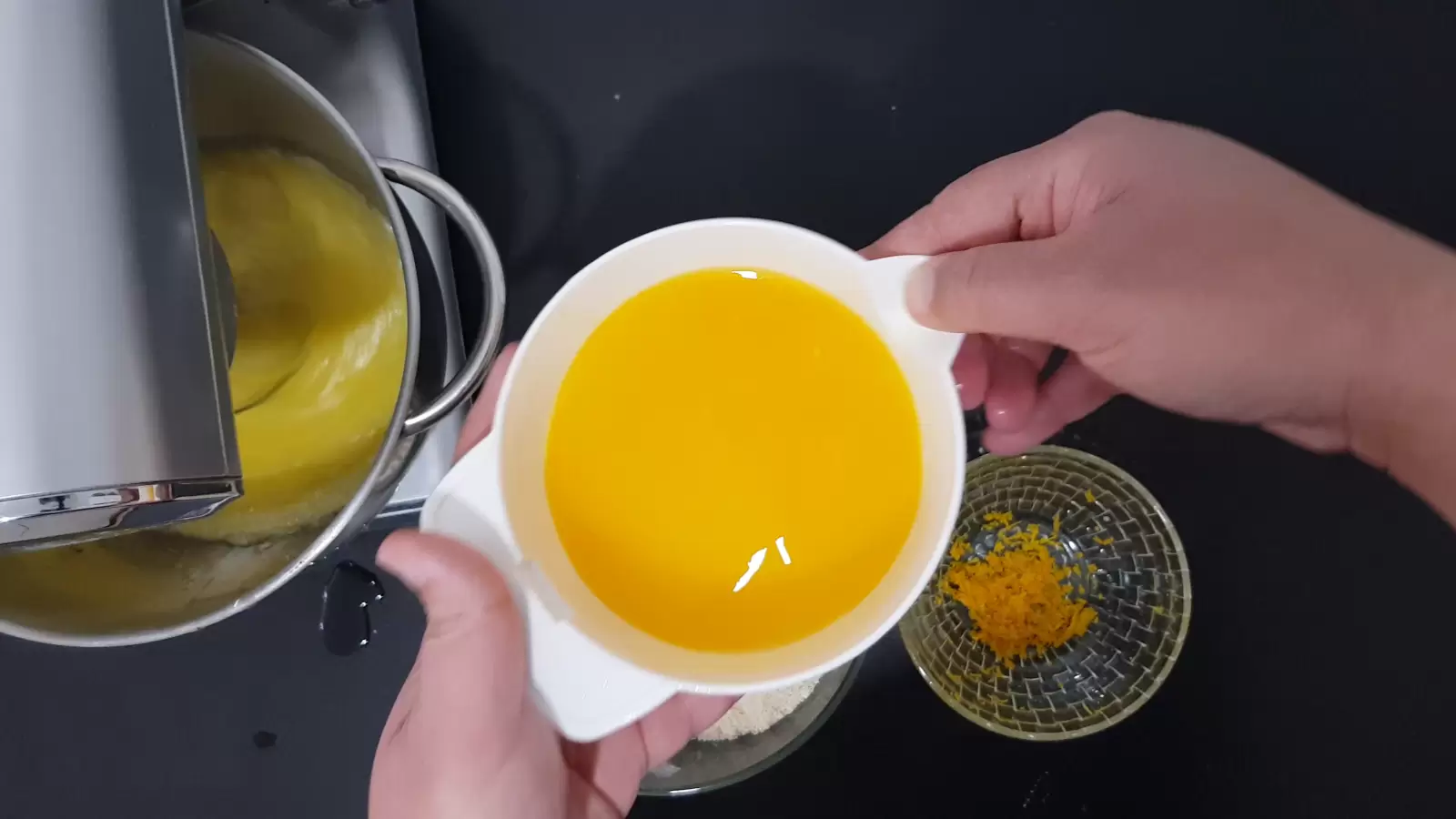 Mixer with batter, bowl with orange zest, bowl with orange juice