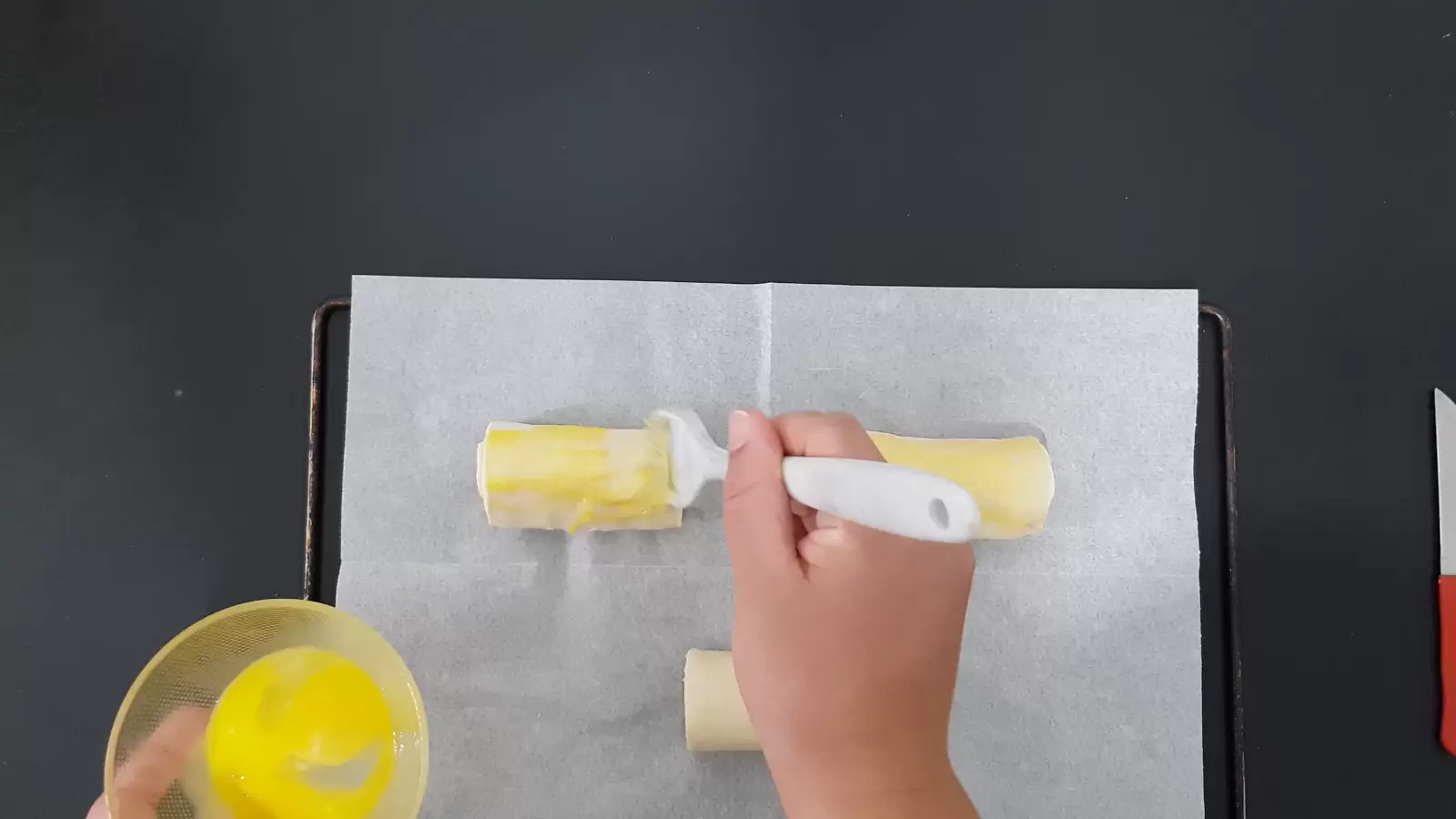 Three Kinder Bueno Croissant on a tray with baking paper, brush spread from a bowl with egg