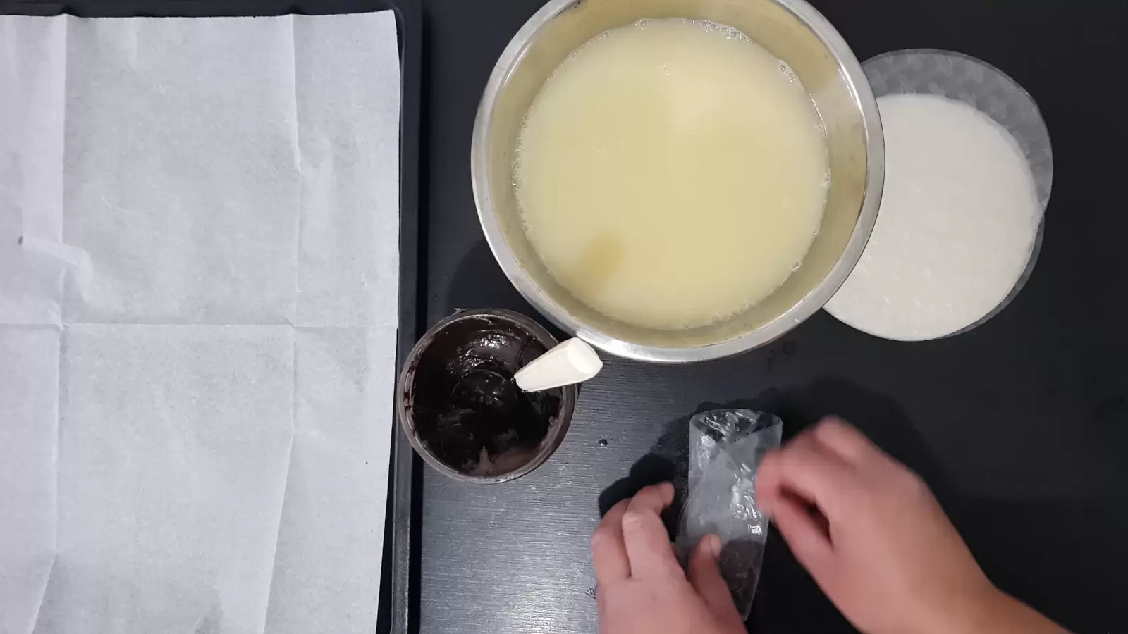 Rice paper, a bowl with water and egg, a jar with chocolate spread and a spoon, rolled rice paper, a baking sheet with baking paper