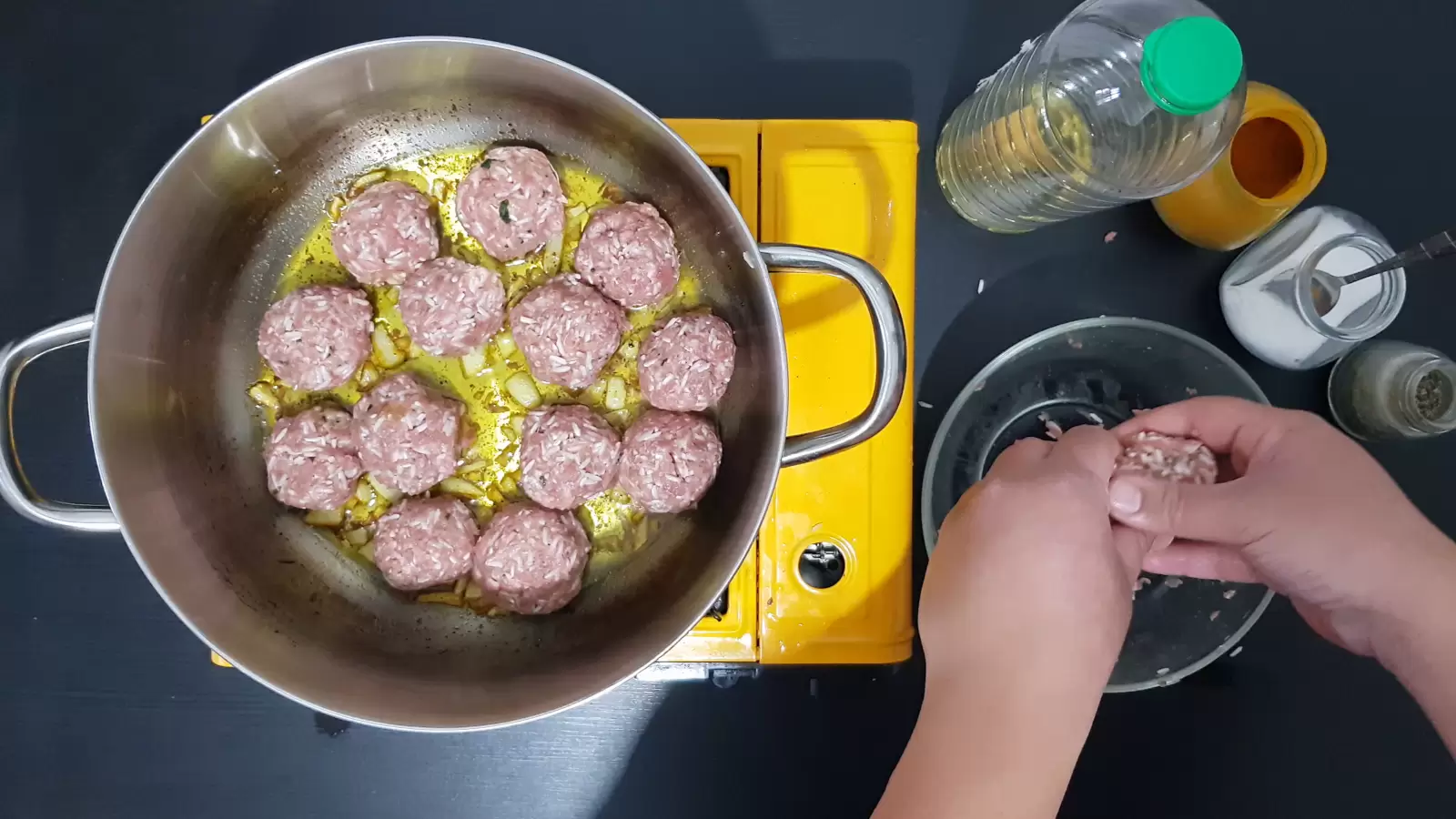 Jar with turmeric, jar with salt, jar with black pepper, bottle of oil, bowl, pot with Porcupine Meatballs