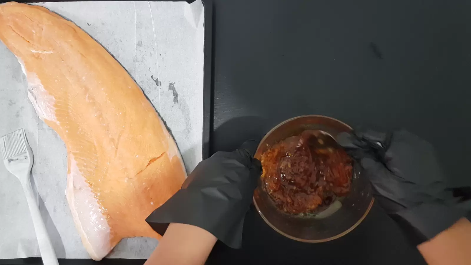 bowl with sauce, baking dish with salmon and brush