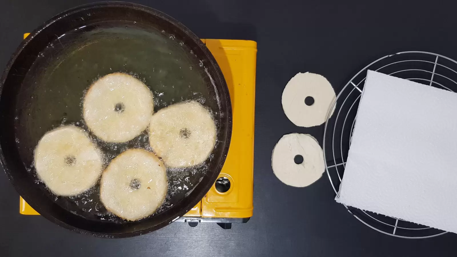 Pan with oil, doughnuts puff pastry, absorbent paper, cooling rack