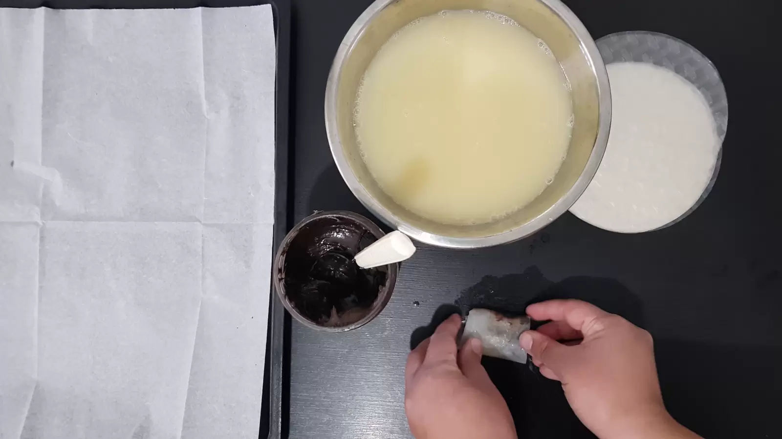 Rice paper, a bowl with water and egg, a jar with chocolate spread and a spoon, rolled rice paper, a baking sheet with baking paper