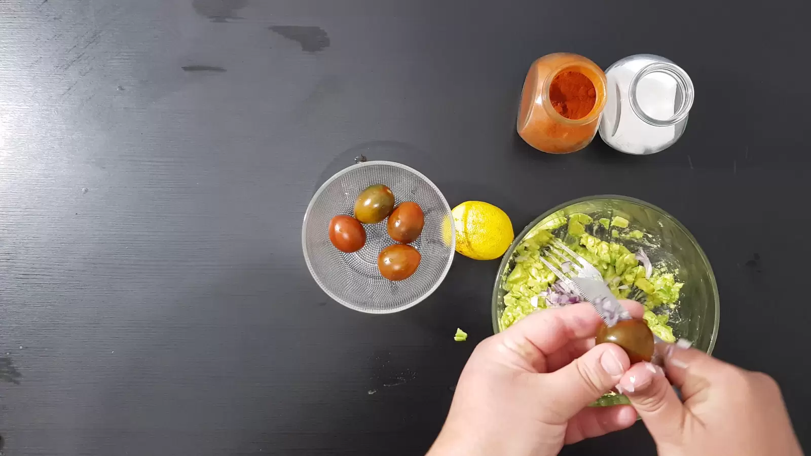 spices, a bowl with tomatoes, lemon, mashed avocado in a bowl, a knife that cuts tomatoes