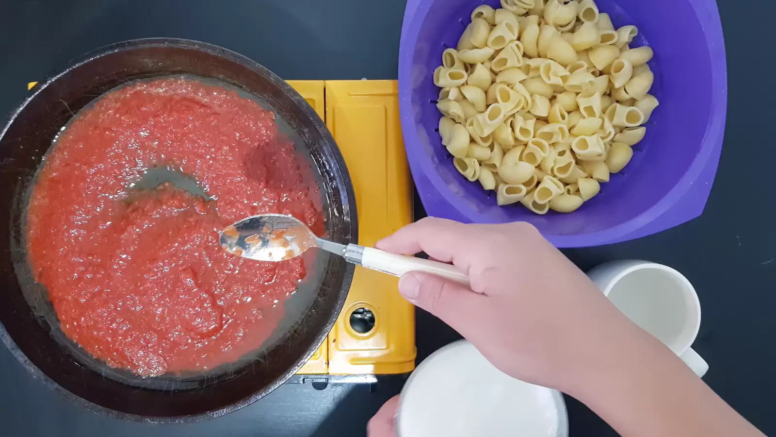 Pan with tomato sauce, bowl with pasta, spoon, glass