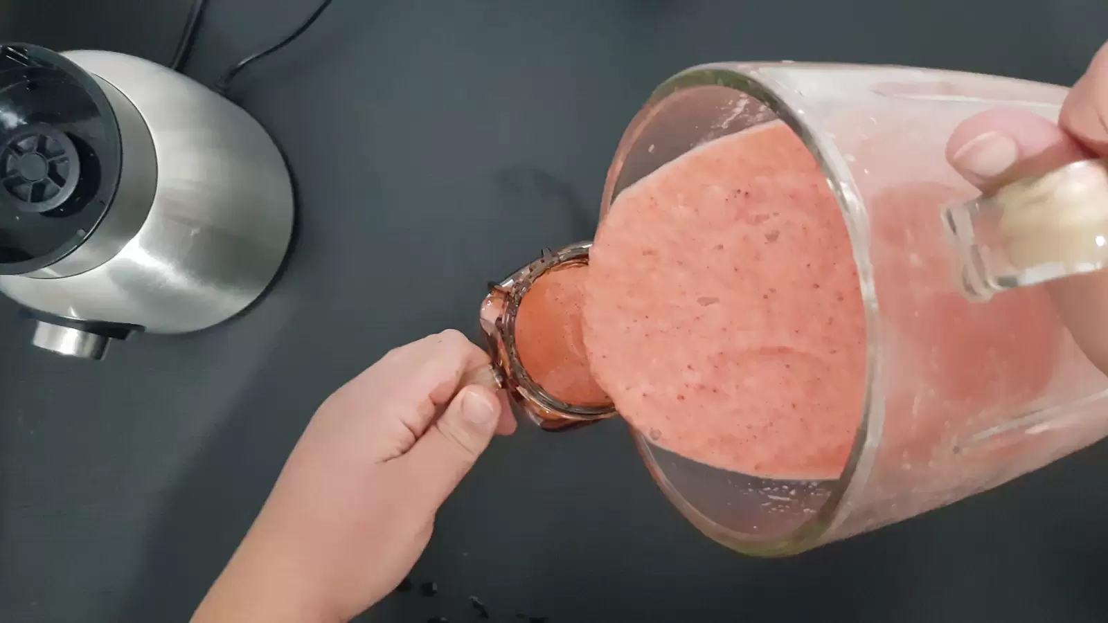 Smoothie is poured into a glass from the blender