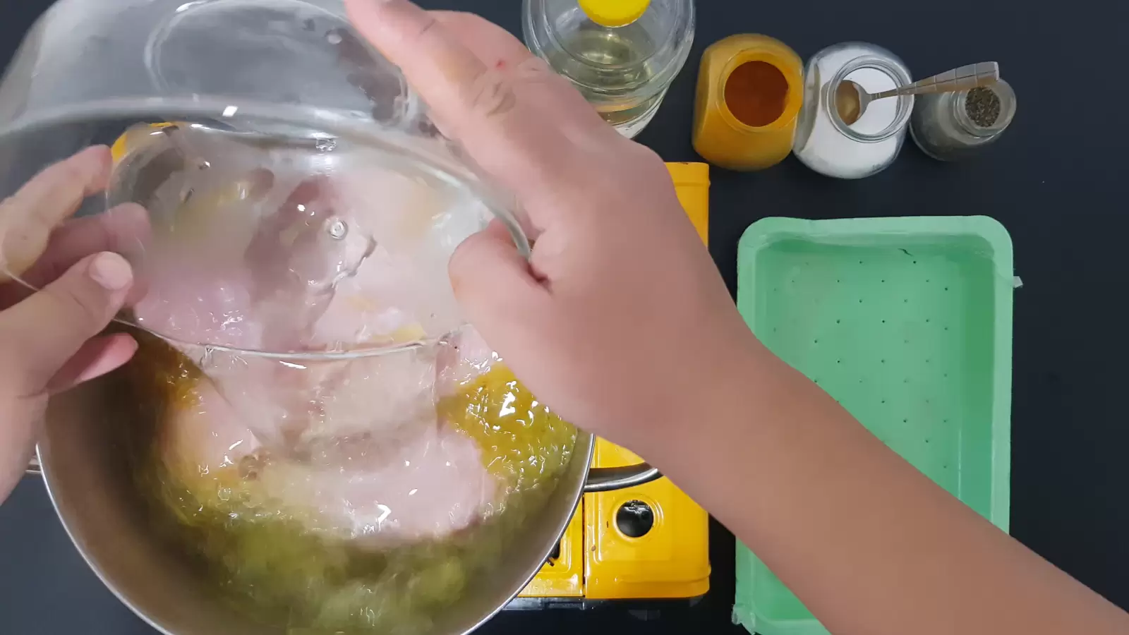 Spices, chicken breast in a pot, water pouring from a bowl