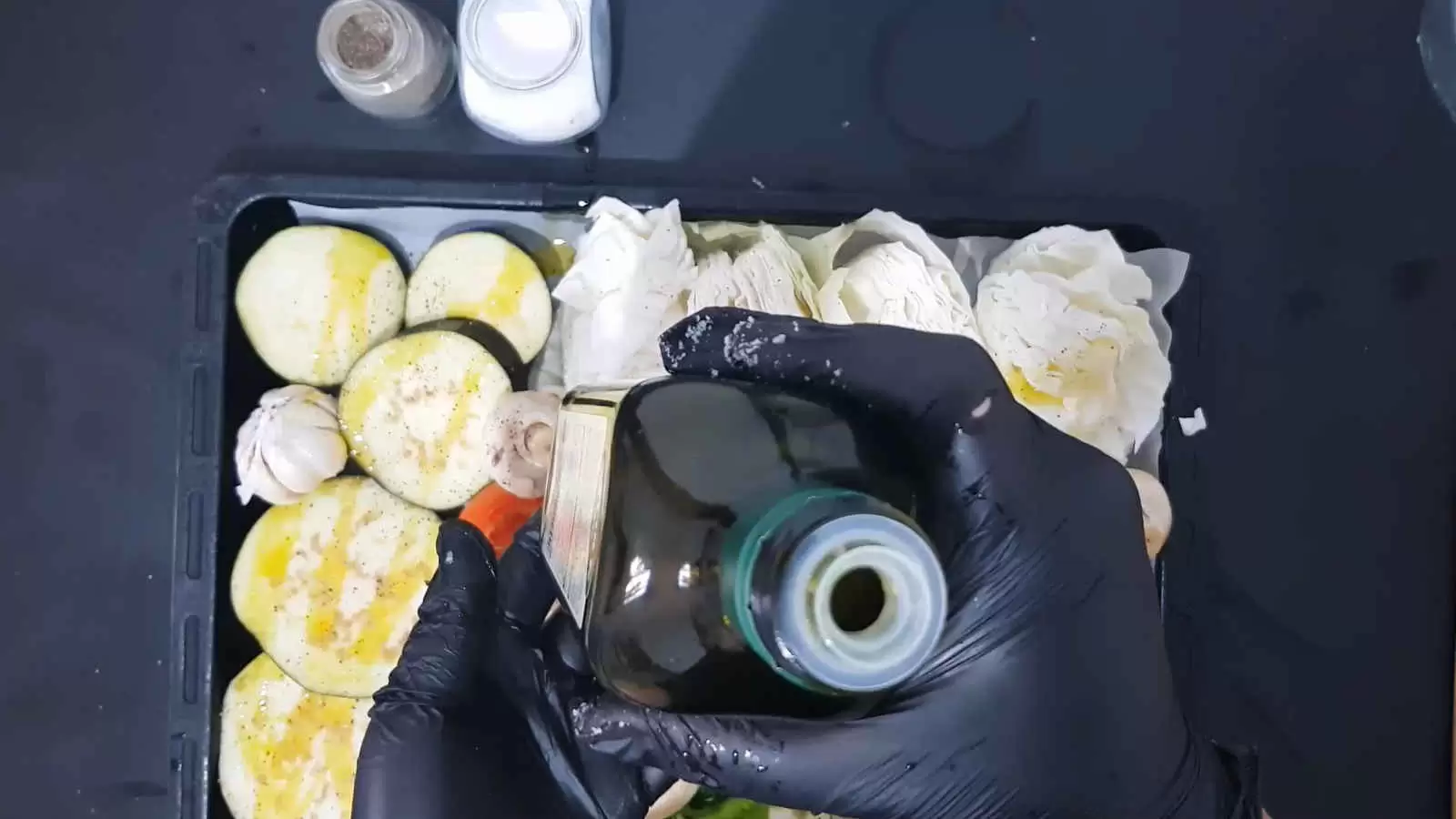 A tray for the oven with vegetables, a bottle of olive oil