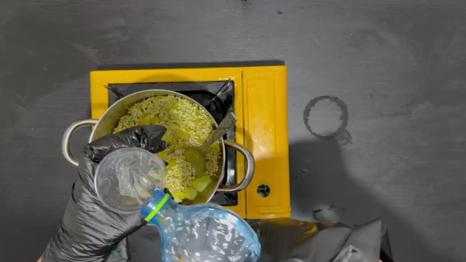 A strainer and pot with Pearl Barley Soup, a bottle of water poured into a glass.