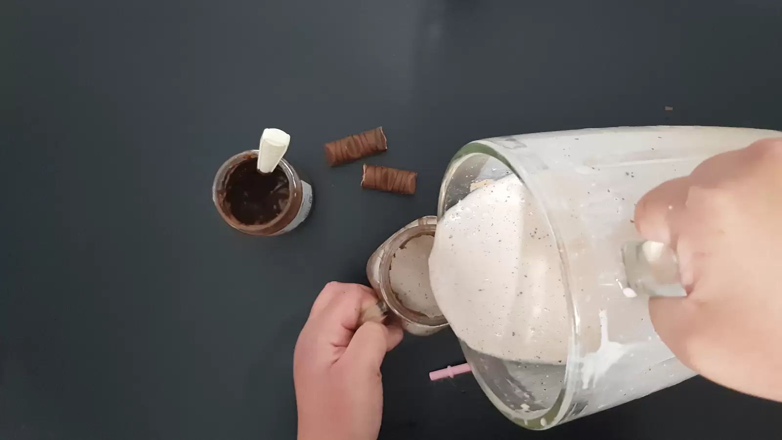 A blender with a milkshake poured into a glass, Kinder Bueno, a jar of Nutella