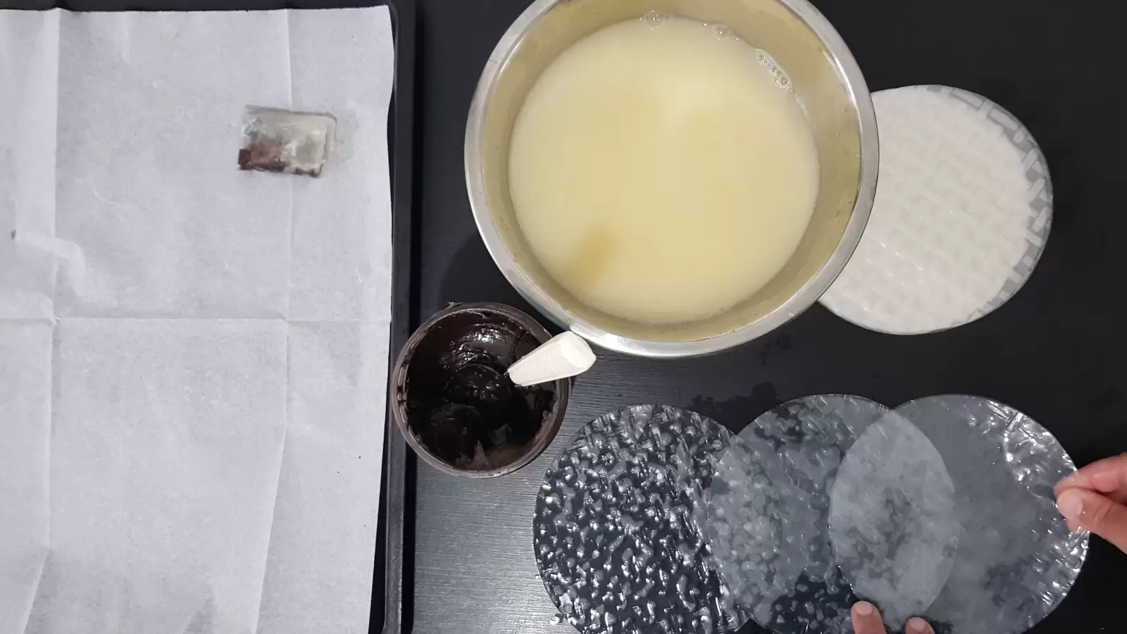 Rice paper, a bowl with water and egg, a jar with chocolate spread and a spoon, three rice papers next to each other, a baking sheet with baking paper and a rice paper pastry