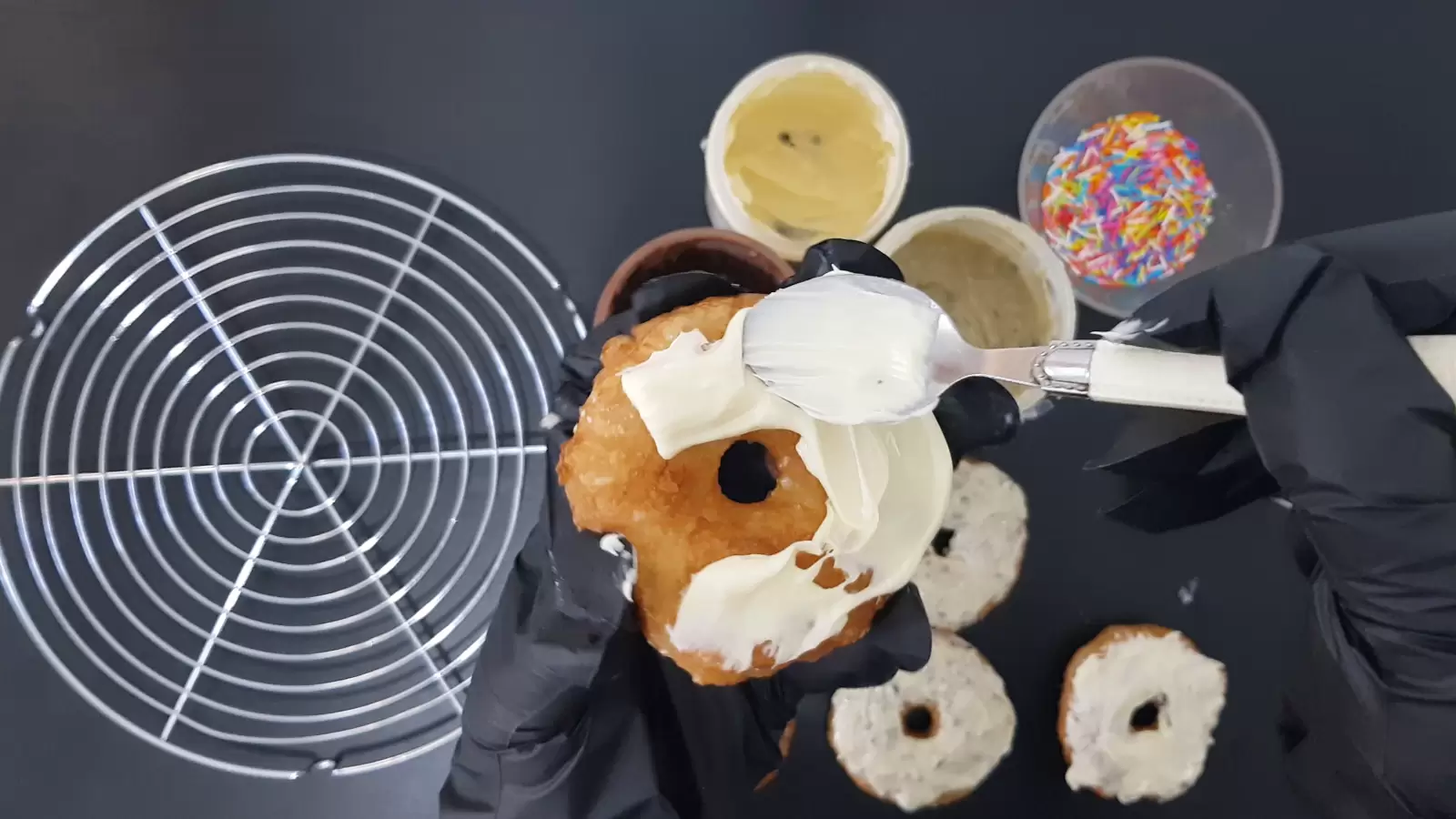 Donuts, rainbow candies, white chocolate spread, spoon, cooling rack