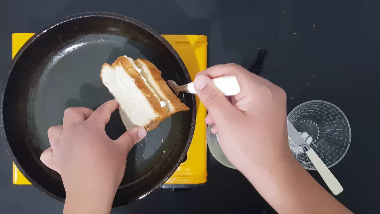 An empty bowl, pick up bread with a fork that is on a pan