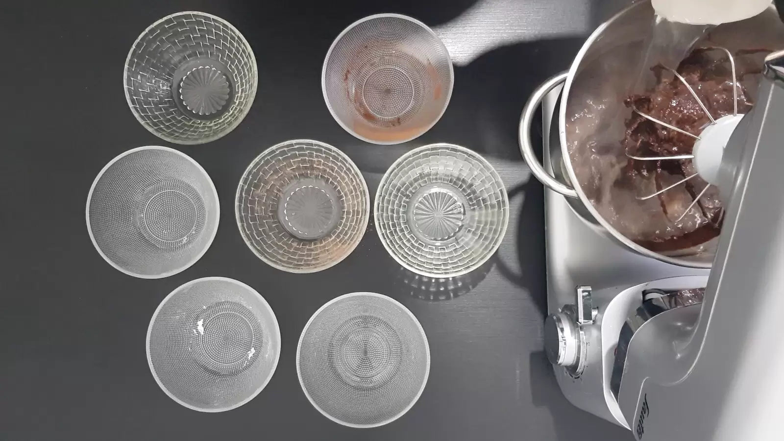 7 empty bowls, mixer with mixture, water poured into it