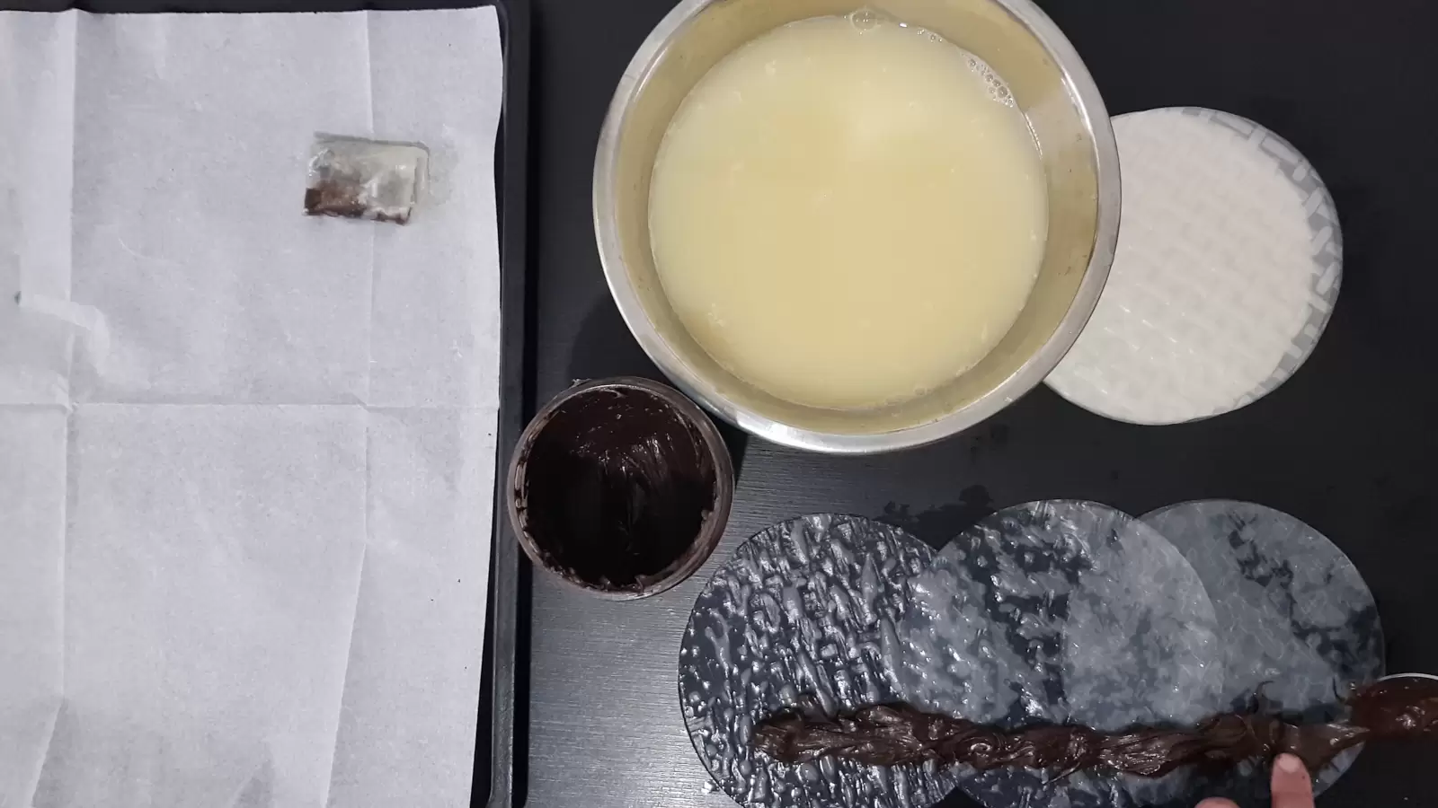 Rice paper, a bowl with water and egg, a jar with chocolate spread and a spoon, three rice papers next to each other and chocolate spread on top, a baking sheet with baking paper and a rice paper pastry