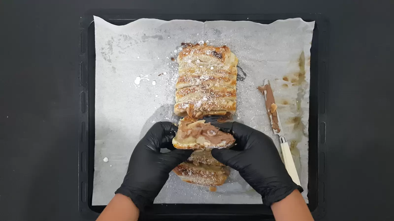 Puff pastry with Milka chocolate on a baking sheet with baking paper and a knife