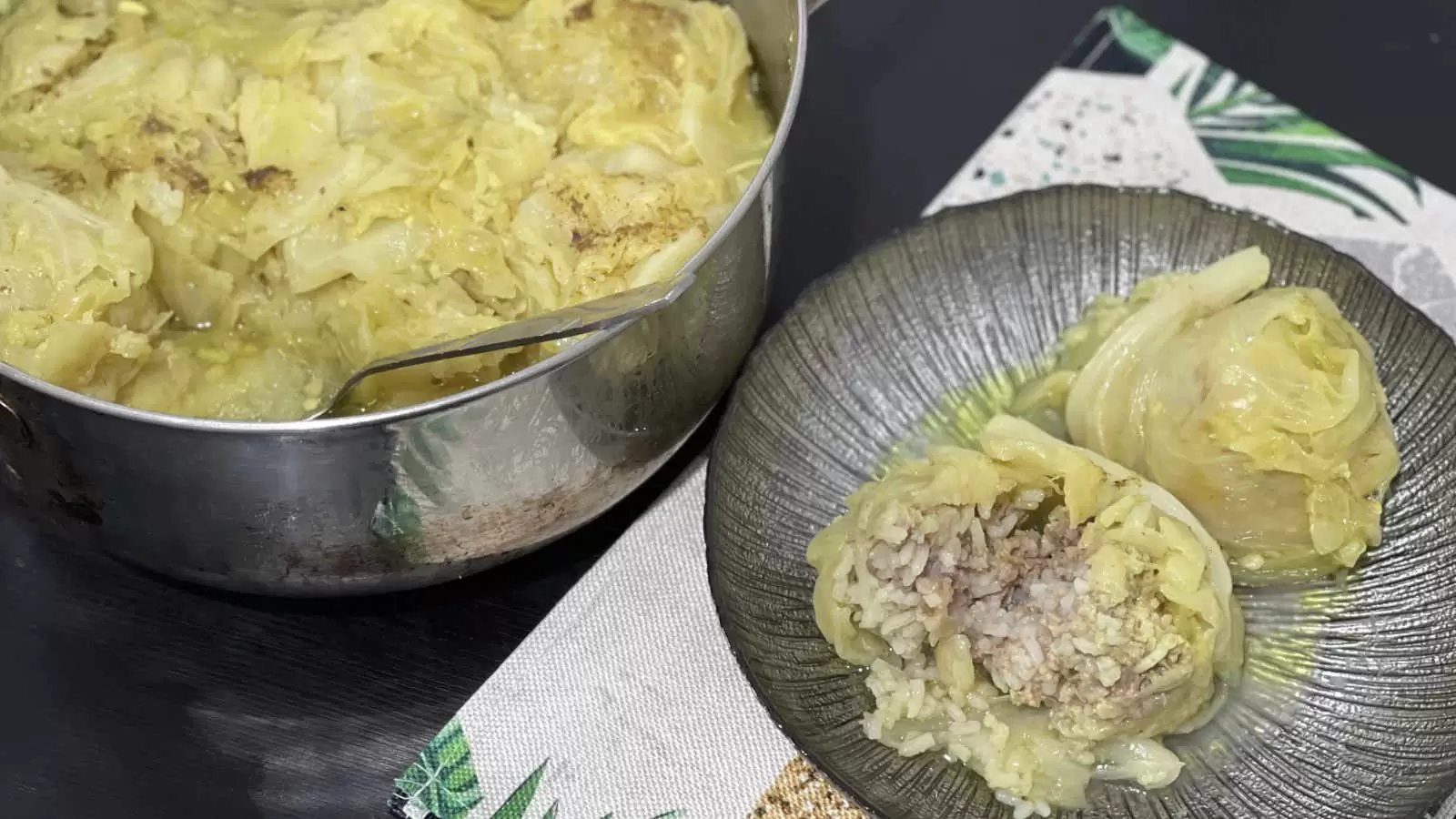 Stuffed Cabbage With Beef And Rice in a pot with a spoon a plate with the dish a napkin underneath