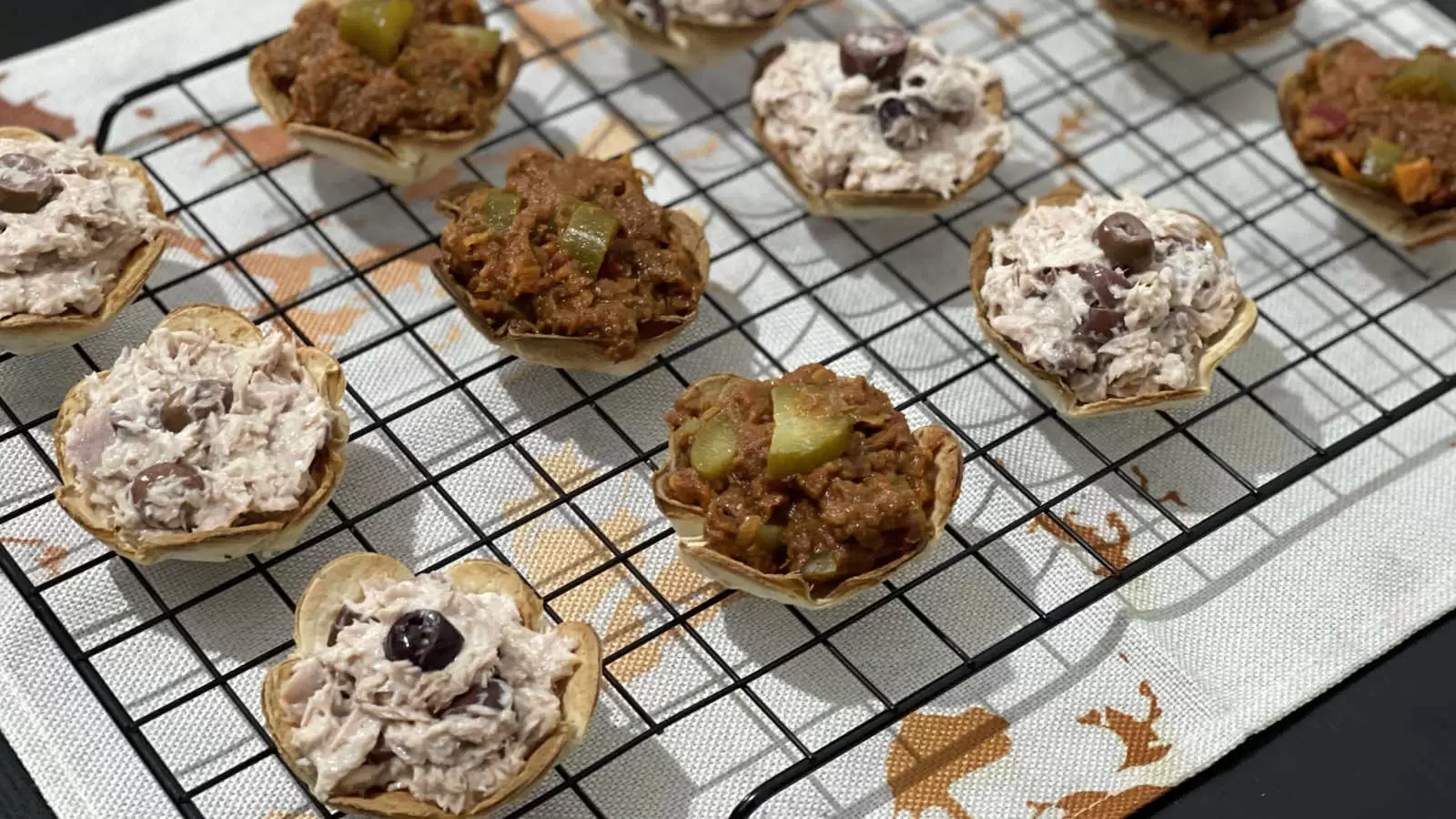 Tortilla flowers filled with tuna on a cooling rack and under a napkin