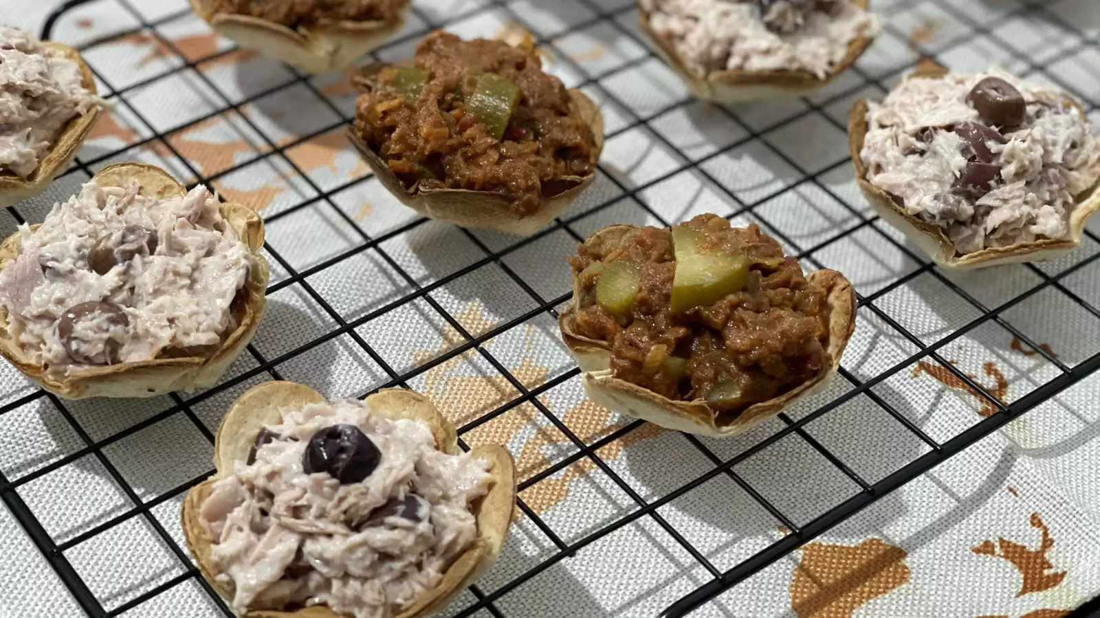 Tortilla flowers filled with tuna dish on a cooling rack and under a napkin